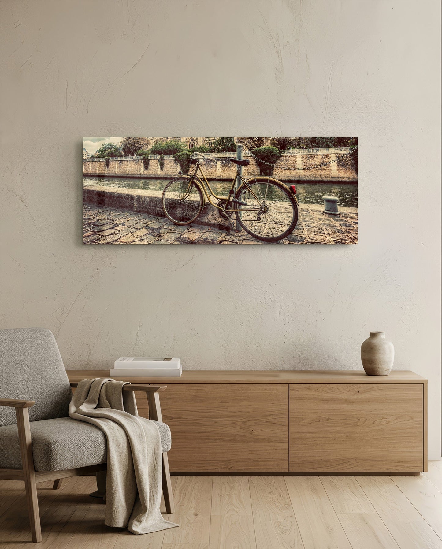 Vintage-style bicycle leaned against stone waterside wall, displayed as horizontal glass wall art above wooden furniture in minimalist room.