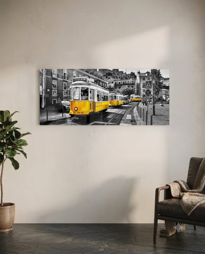 Yellow vintage tram on black and white Lisbon street scene displayed as glass wall art above leather chair in modern interior.