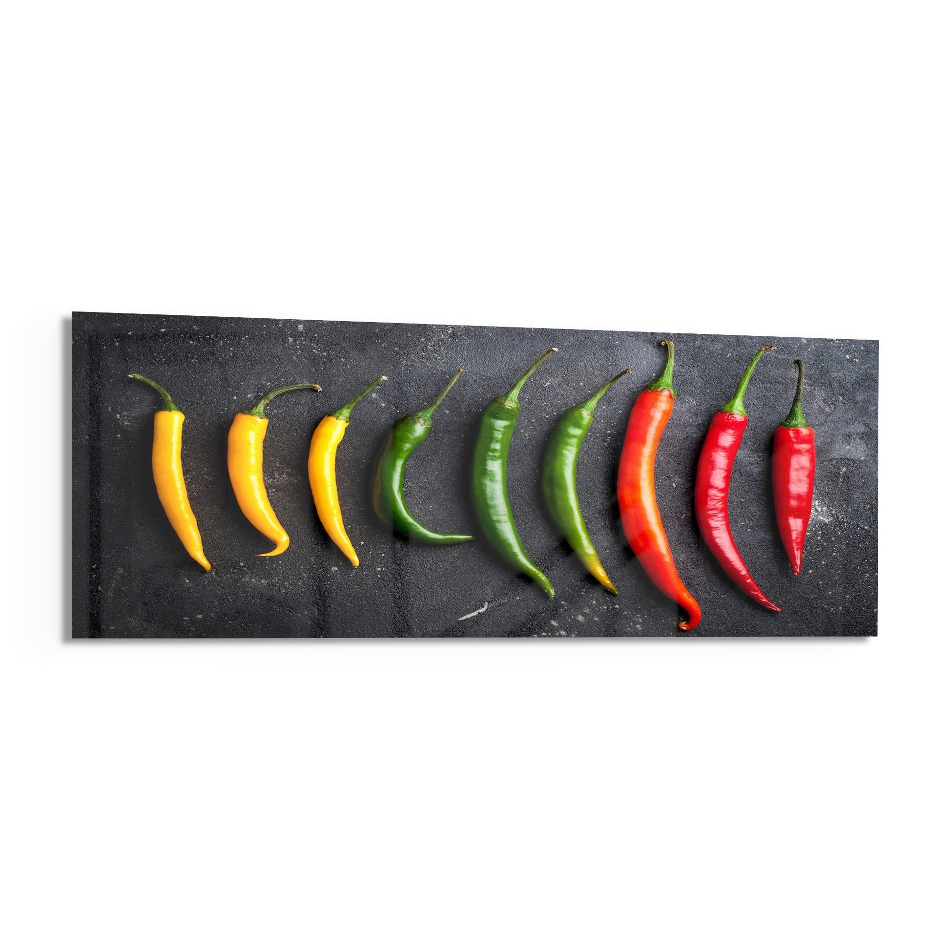 Nine fresh chili peppers in yellow, green, and red arranged in a color gradient on a dark textured surface.