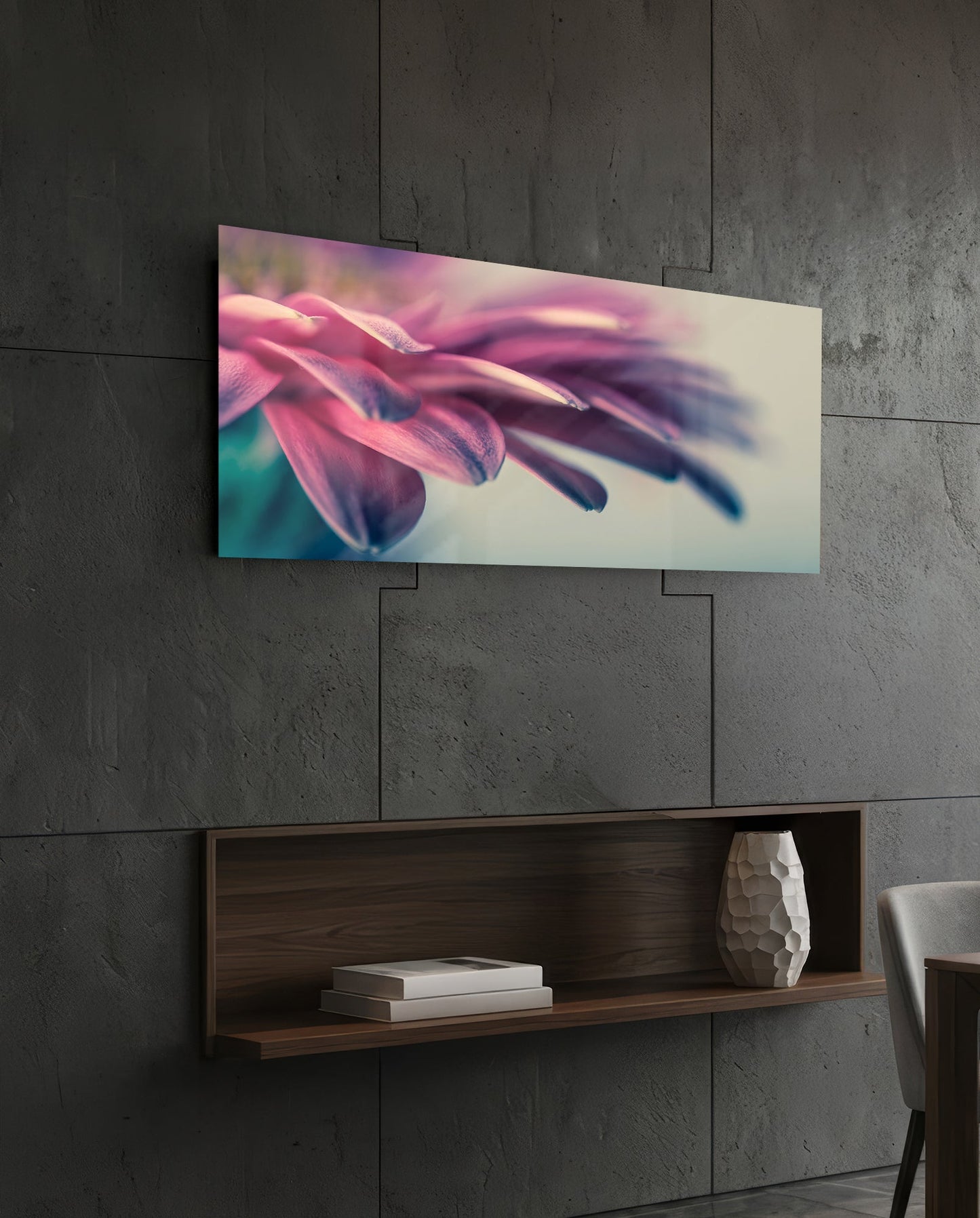 Horizontal glass wall art displaying close-up pink flower petals with soft teal accents, mounted on concrete wall above wooden shelf.