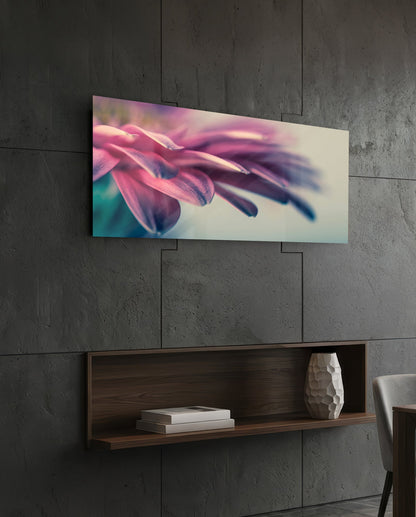 Horizontal glass wall art displaying close-up pink flower petals with soft teal accents, mounted on concrete wall above wooden shelf.