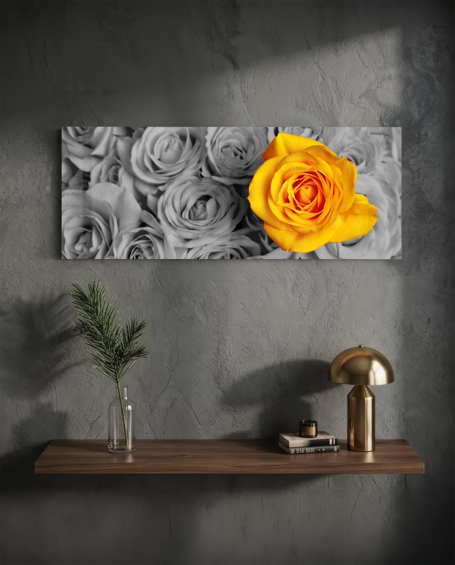 Yellow rose glass wall art hanging above wooden shelf with brass lamp, vase, and books in minimalist interior setting.
