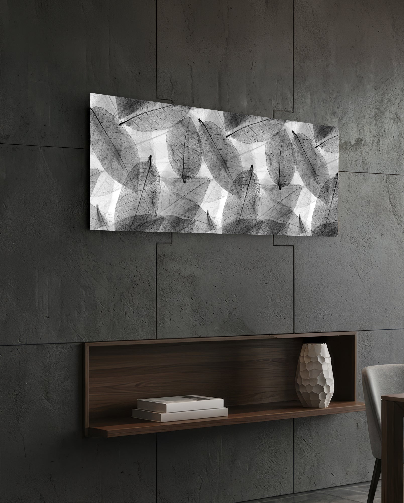 Black and white leaf-patterned glass art displayed horizontally above a wooden shelf on a concrete wall.
