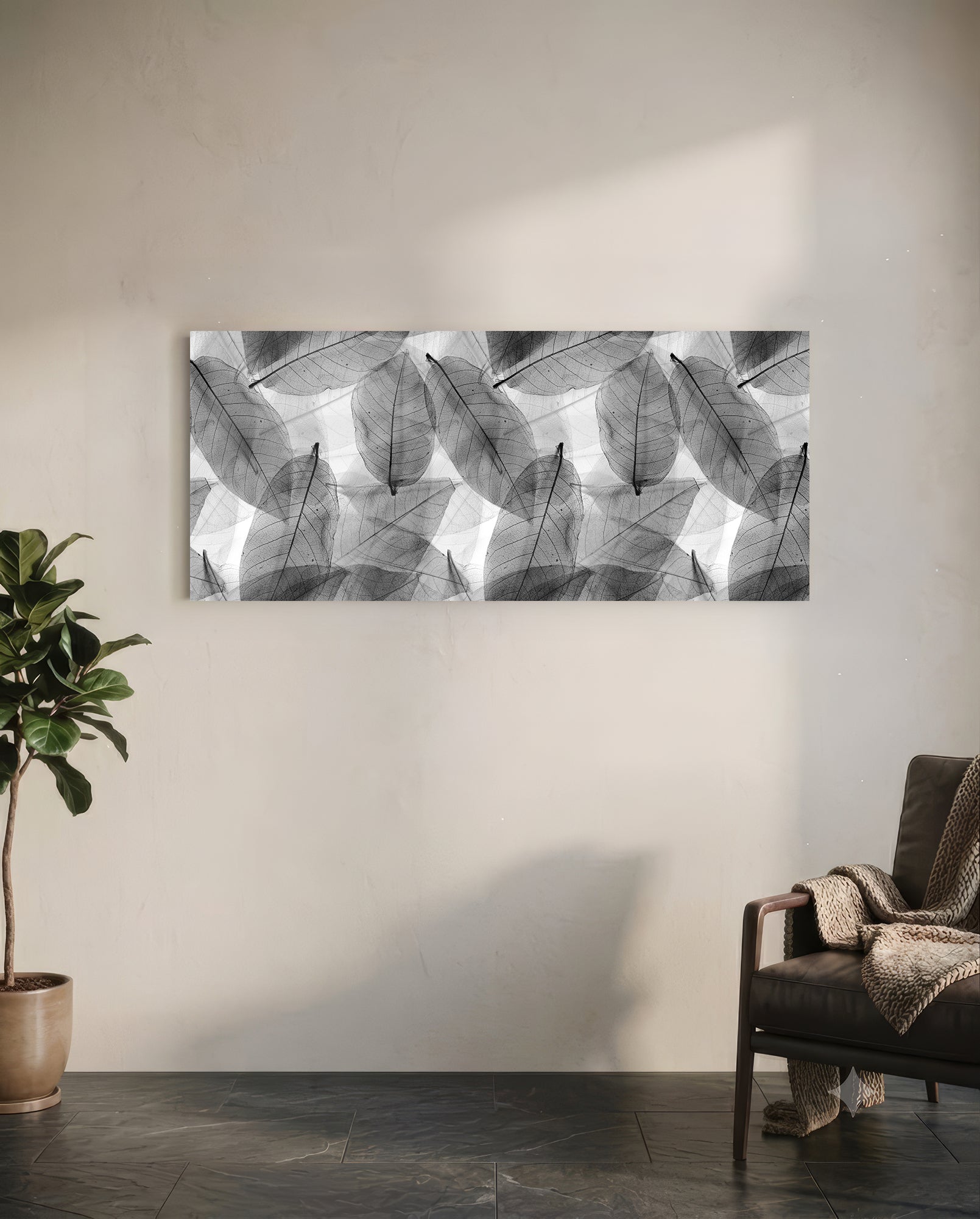 Black and white translucent leaf pattern glass wall art hanging above a leather chair in a minimalist room setting.