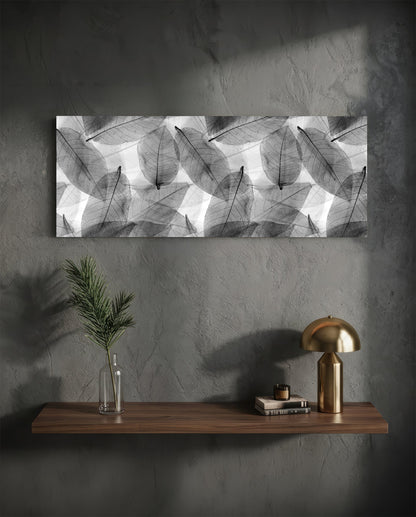 Black and white translucent leaf pattern glass art mounted horizontally above wooden shelf with brass lamp and decorative items.