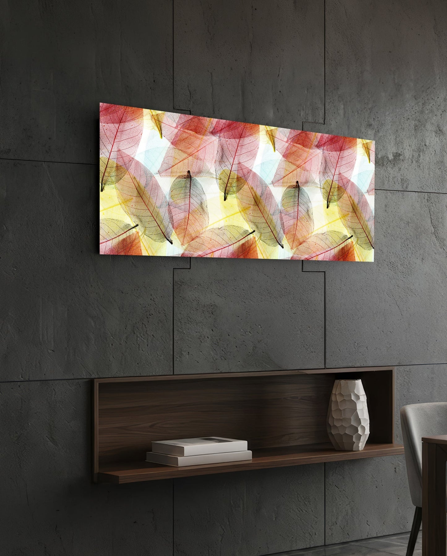 Rectangular glass wall art with translucent red, yellow, and green leaves displayed above a wooden shelf on concrete wall.