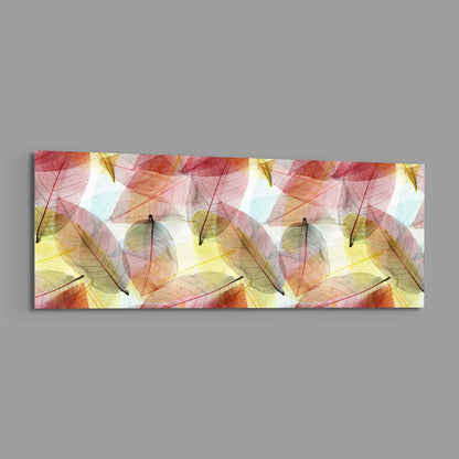 Horizontal glass wall art panel displaying translucent autumn leaves in red, pink, yellow, and green tones on white background.