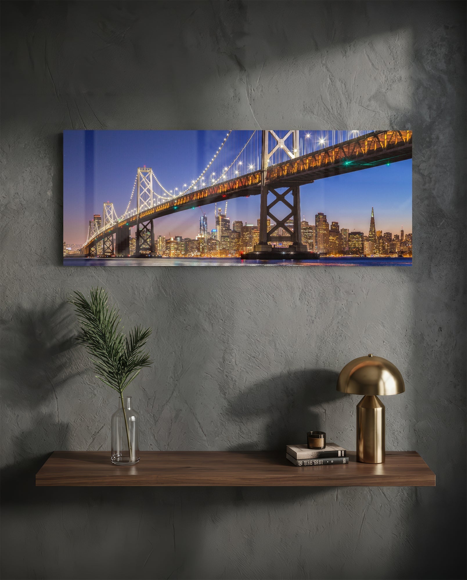 Bridge Glass Wall Art mounted above wooden shelf displaying San Francisco Bay Bridge illuminated at dusk with city skyline.