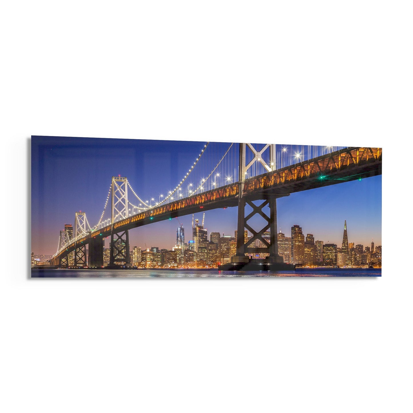 Bay Bridge illuminated at dusk with San Francisco skyline glowing against twilight blue sky, displayed as horizontal glass wall art.
