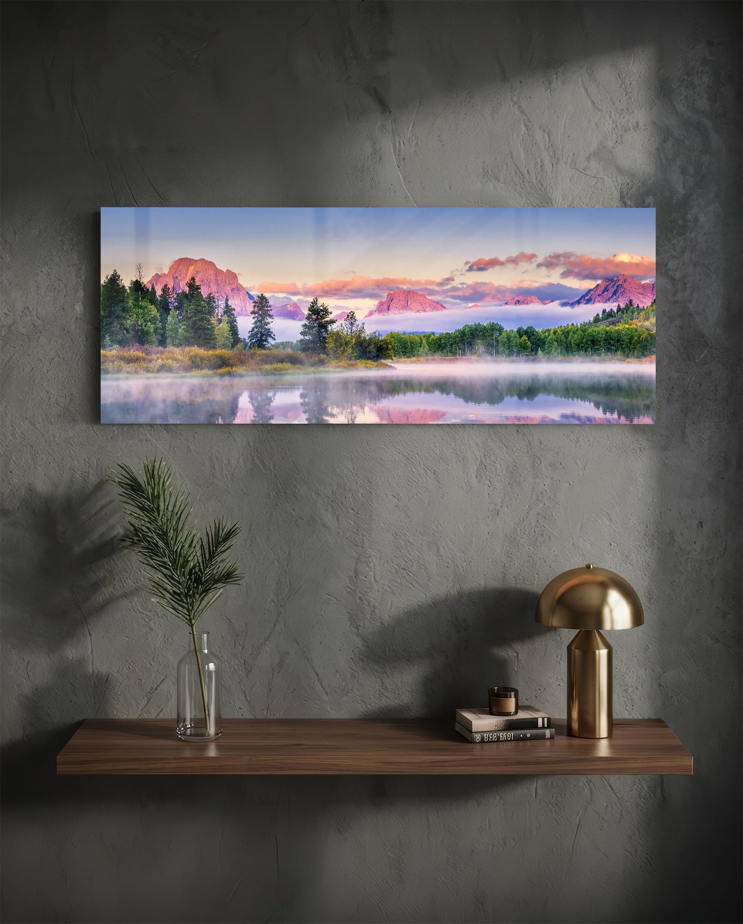 Landscape glass wall art displaying a misty lake with snow-capped mountains at sunrise, hung above a wooden shelf.