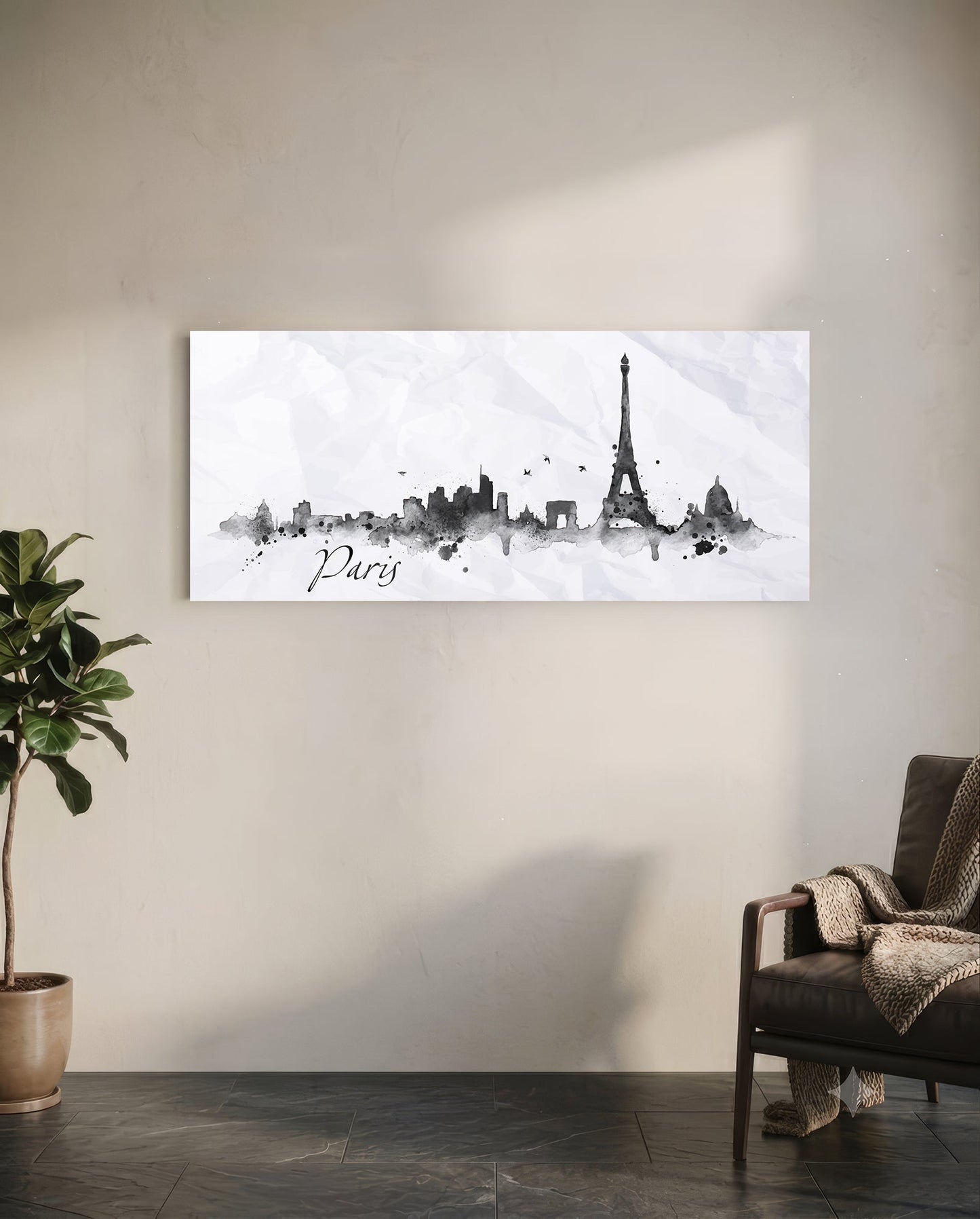 Paris skyline watercolor art in black and gray tones hanging on white wall above potted plant and chair.