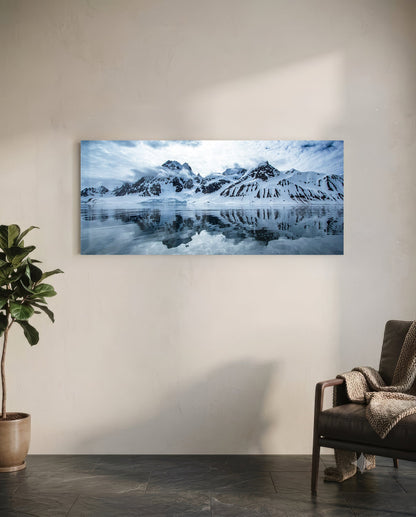 Snowy mountain landscape glass wall art hanging above a leather chair in a minimalist interior space.