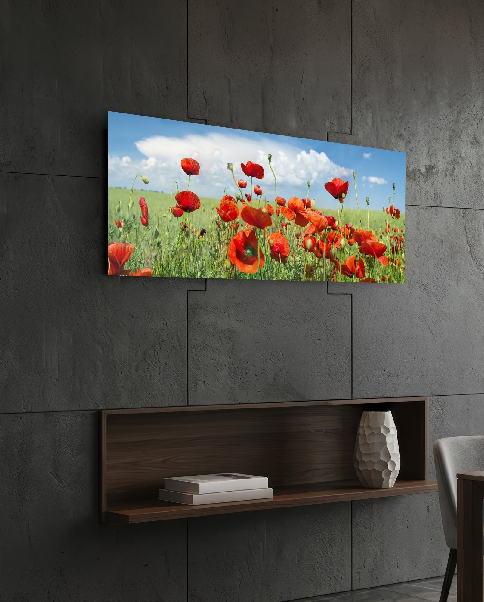Poppy flower glass wall art mounted on dark concrete wall above wooden shelf with books and white vase.