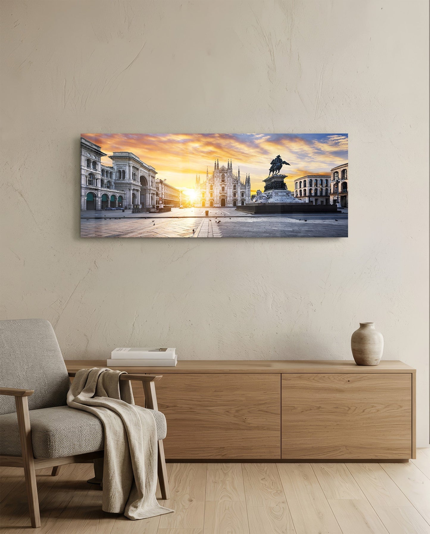 Horizontal glass wall art depicting Milan's Duomo cathedral at golden sunrise, mounted above wooden cabinet in minimalist interior.