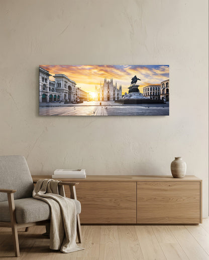 Horizontal glass wall art depicting Milan's Duomo cathedral at golden sunrise, mounted above wooden cabinet in minimalist interior.