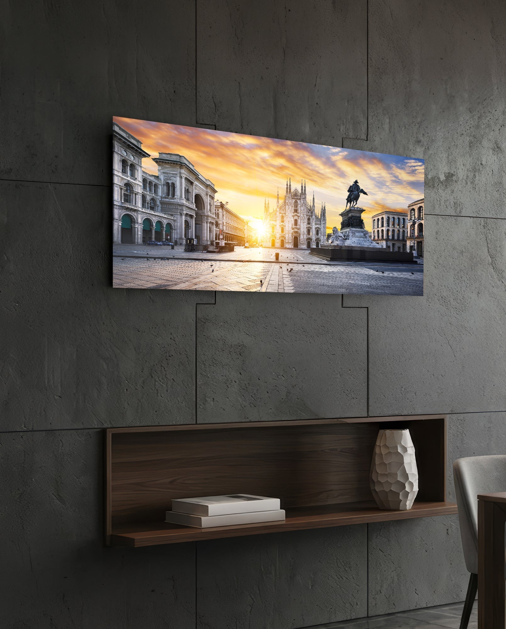 Horizontal glass wall art depicting Milan's Piazza Duomo at sunset, mounted above wooden shelf on concrete wall.