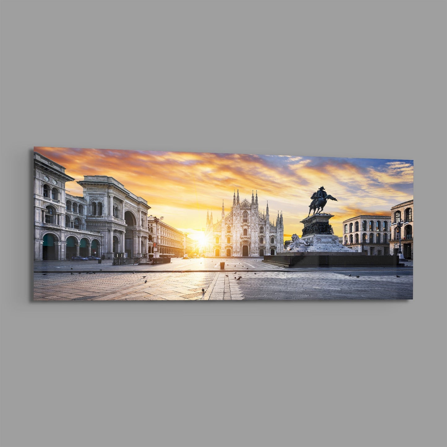 Panoramic glass wall art depicting Milan's Piazza Duomo at golden sunrise with cathedral, historic buildings, and equestrian statue.