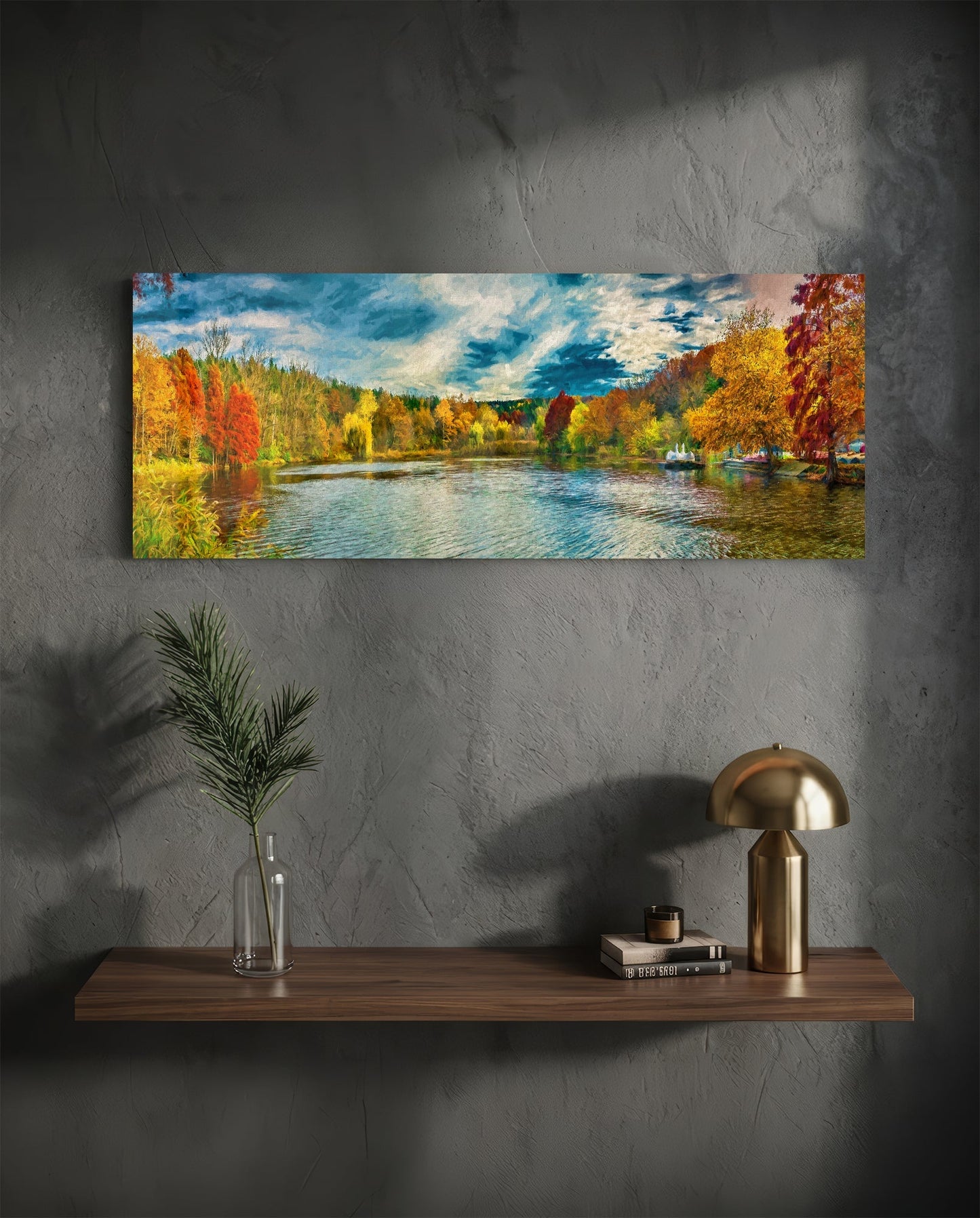 Horizontal glass art panel mounted on gray wall above wooden shelf, displaying autumn river landscape with colorful fall foliage and blue sky.