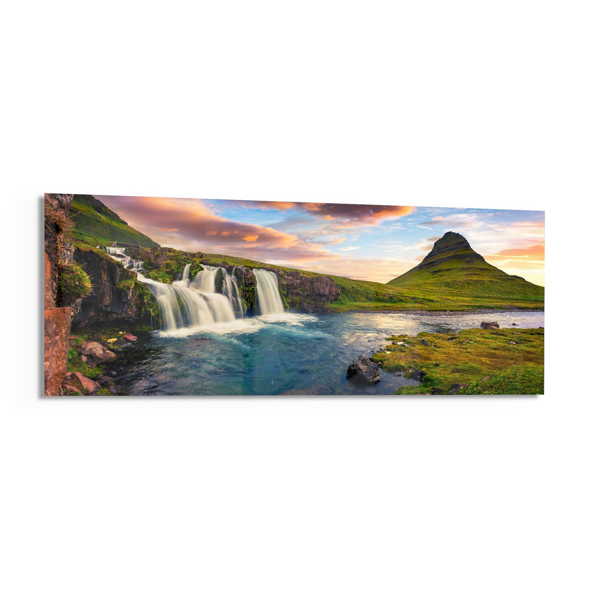 Panoramic glass wall art displaying an Icelandic landscape with cascading waterfall, turquoise stream, moss-covered mountain, and sunset sky.