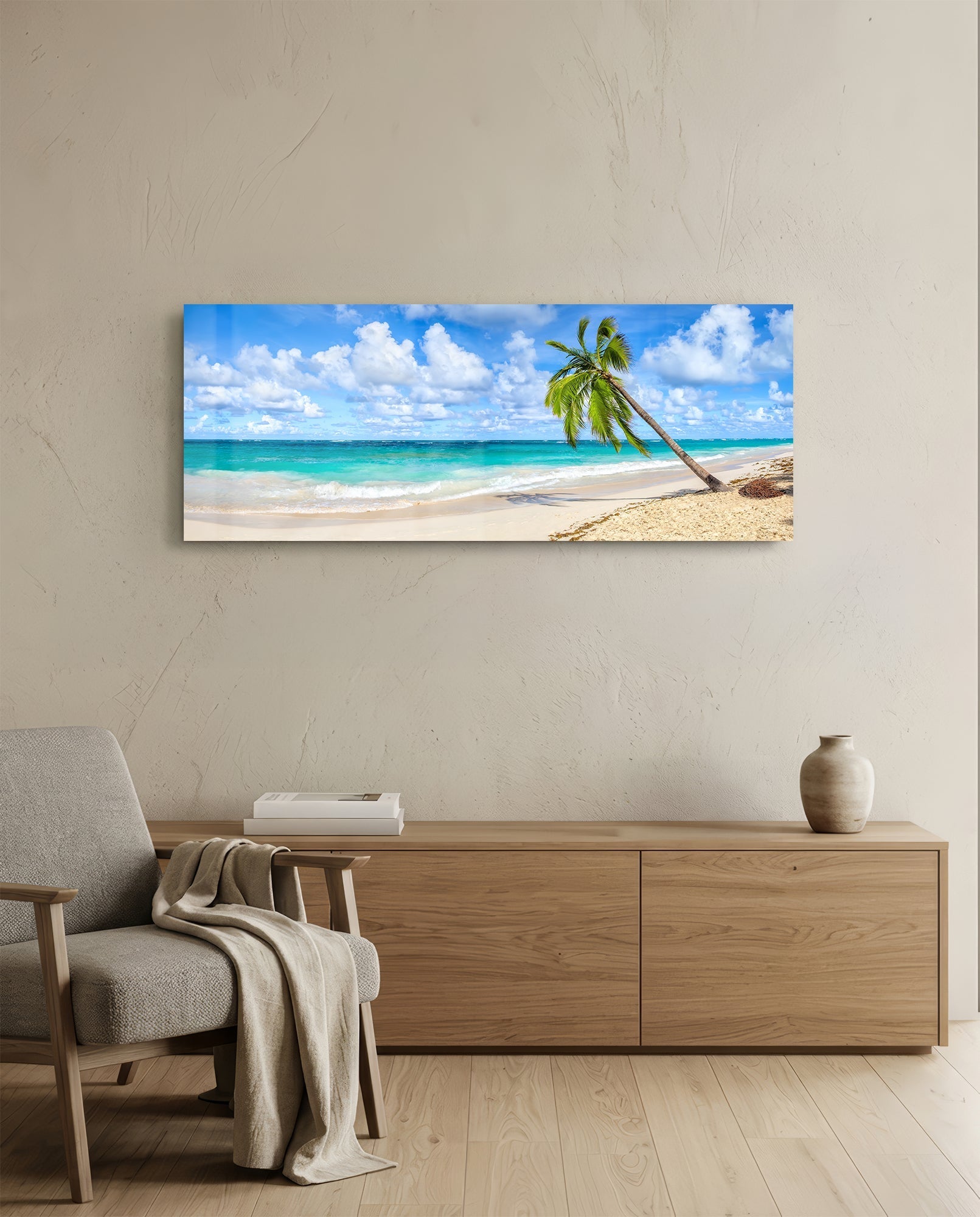 Tropical beach glass wall art displayed above wooden dresser in neutral interior, showing palm tree, sand, turquoise ocean, and blue sky.