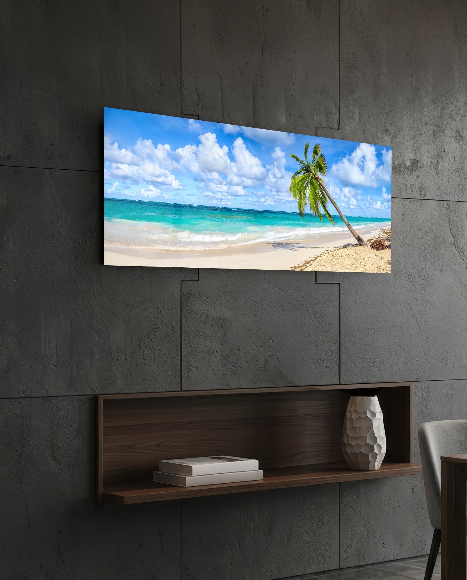 Tropical beach glass wall art displaying turquoise ocean and leaning palm tree mounted above wooden shelf on concrete wall.