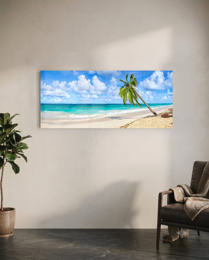 Palm tree glass wall art hanging on white wall above leather chair, showing tropical beach scene with turquoise ocean and white sand.