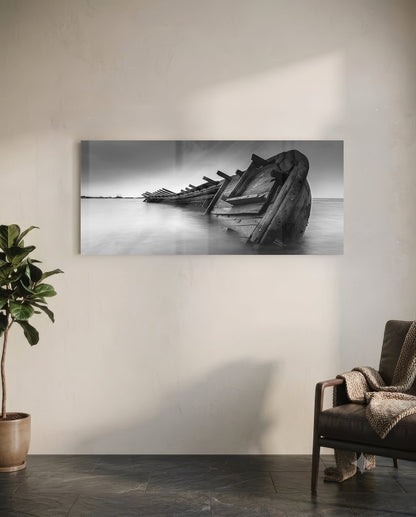Black and white framed shipwreck glass art hanging on white wall above leather chair and potted plant.