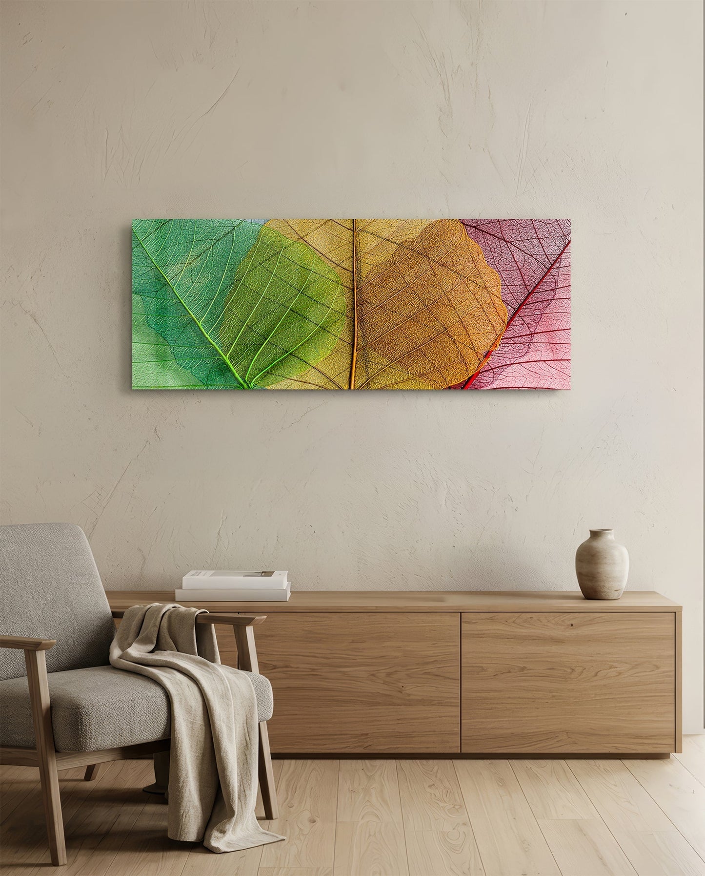 Colorful glass wall art with translucent green, yellow, orange, and pink leaf designs displayed above wooden furniture in a minimalist interior.