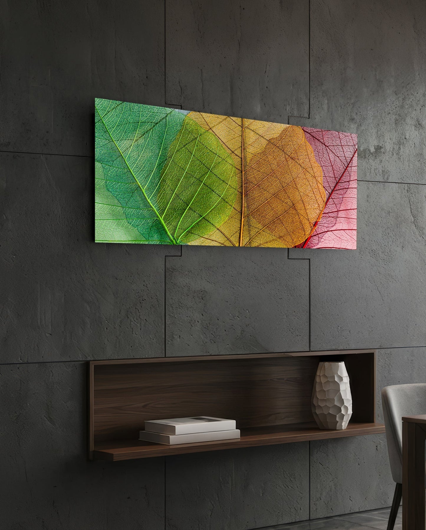 Colorful gradient glass wall art displaying overlapping leaf veins in green, yellow, orange, and pink tones, mounted on concrete wall above wooden shelf.
