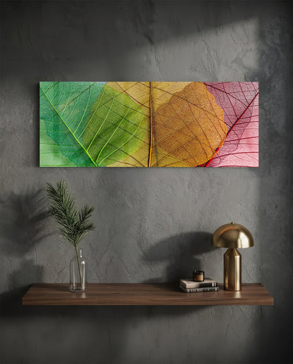 Colorful glass leaf wall art with green, yellow, orange, and pink gradient displayed above wooden shelf with brass lamp and plant vase.