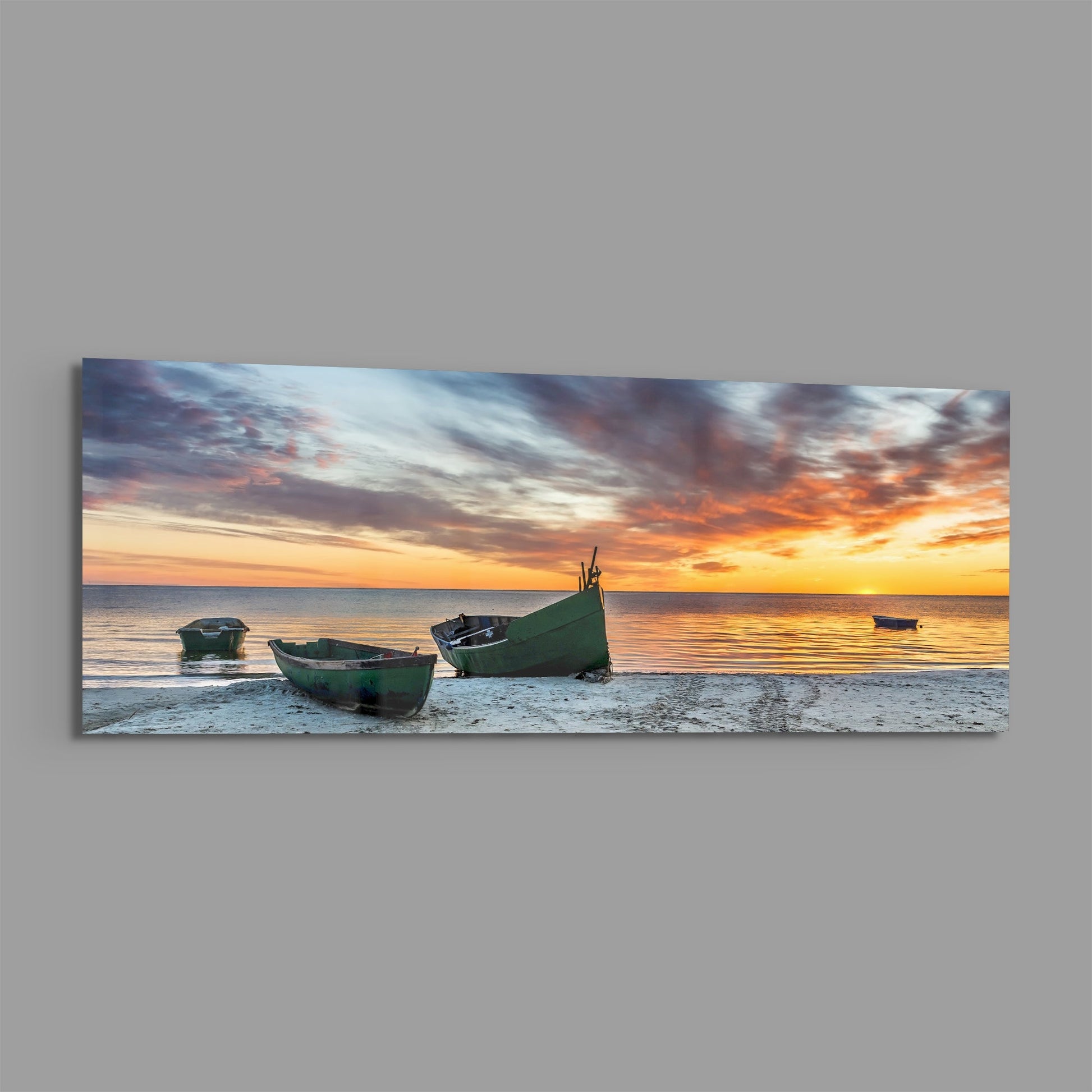 Three weathered green boats rest on sand at sunset, with golden-orange sky and calm sea reflecting warm light.
