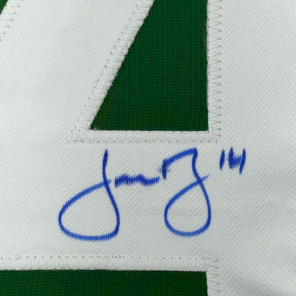 Close-up of green jersey fabric with blue handwritten signature and number 14 on white panel.