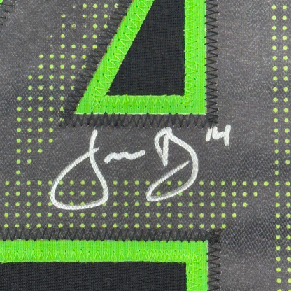 Close-up of neon green binding trim and white signature on dark grey jersey fabric with yellow dot pattern.