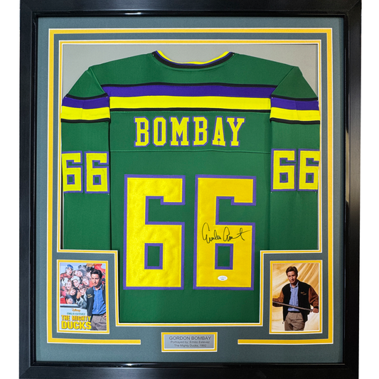 Framed green hockey jersey with "BOMBAY" and number 66 in yellow, signed by Emilio Estevez, flanked by two photos from The Mighty Ducks movie.