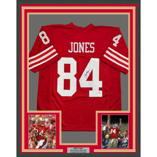Red San Francisco 49ers jersey number 84 signed by Brent Jones, displayed in frame with photos and nameplate.