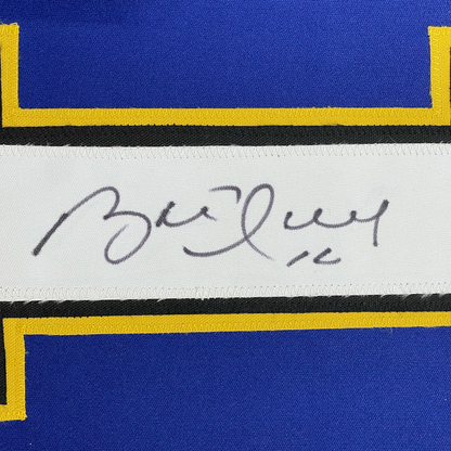Close-up of handwritten signature on white label strip between blue and yellow striped jersey fabric.