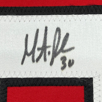 Close-up of Martin Brodeur's handwritten signature in black ink on white fabric with red and black striped jersey trim.
