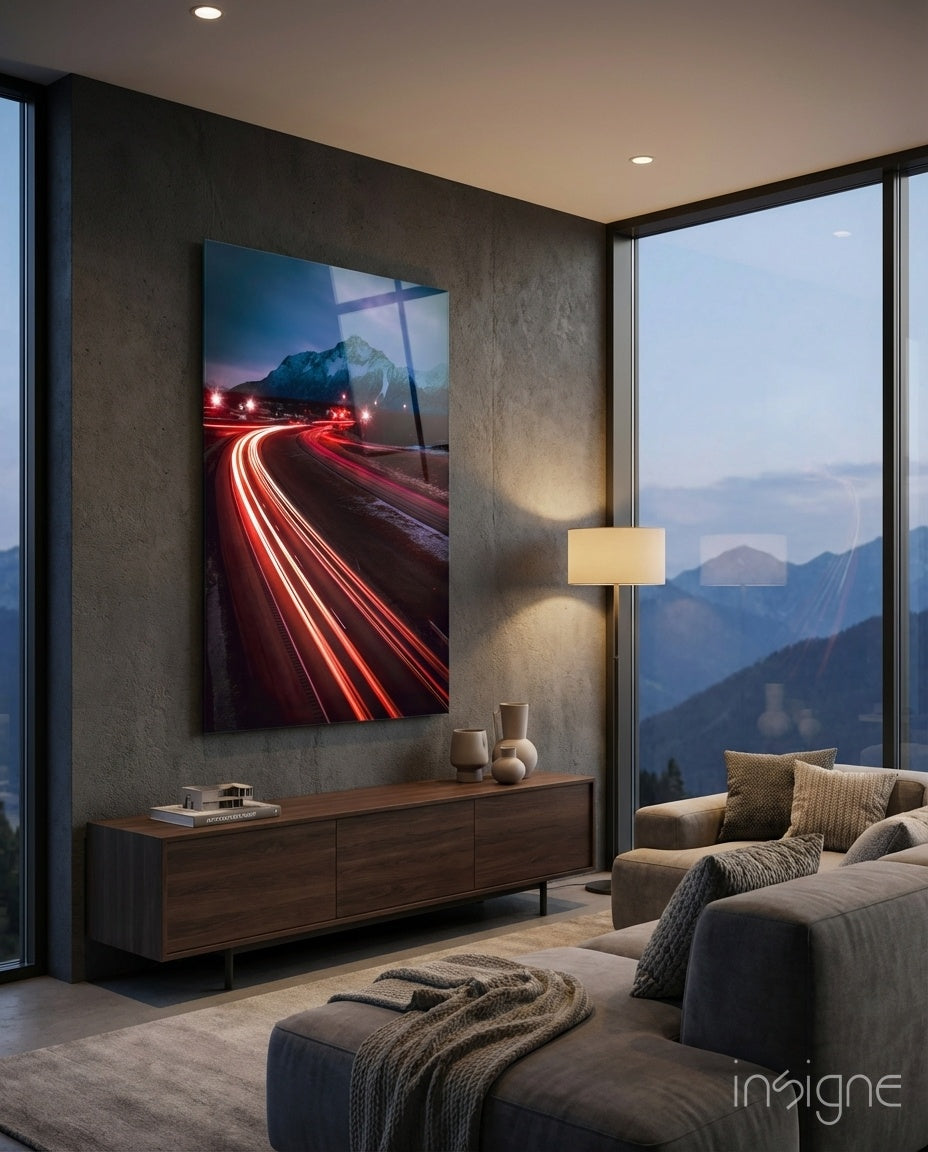 Road Glass Wall Art displaying red car light trails and mountain peak, mounted above wooden console in modern living room with mountain views.