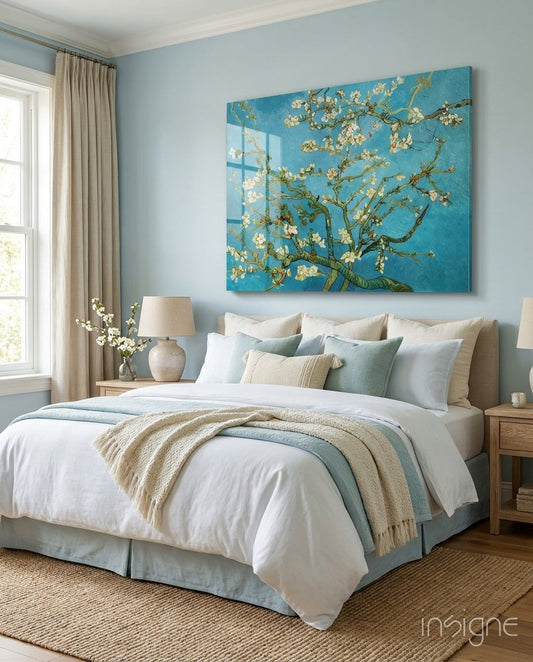 Glass wall art featuring white blossoms on turquoise branches displayed above a bed in a light blue bedroom.