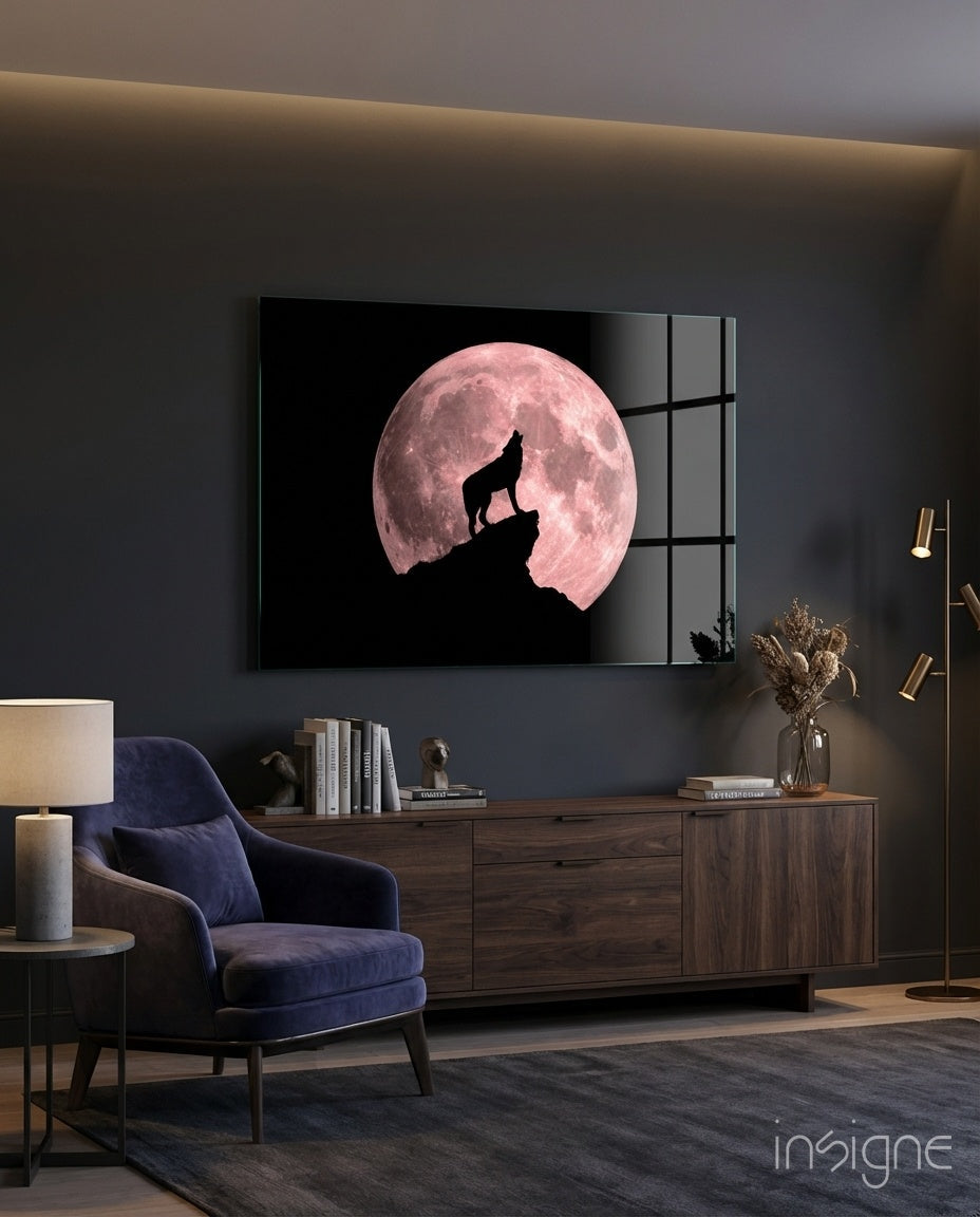 Wolf howling silhouette against pink full moon on black glass panel mounted above wooden media console in modern living room.