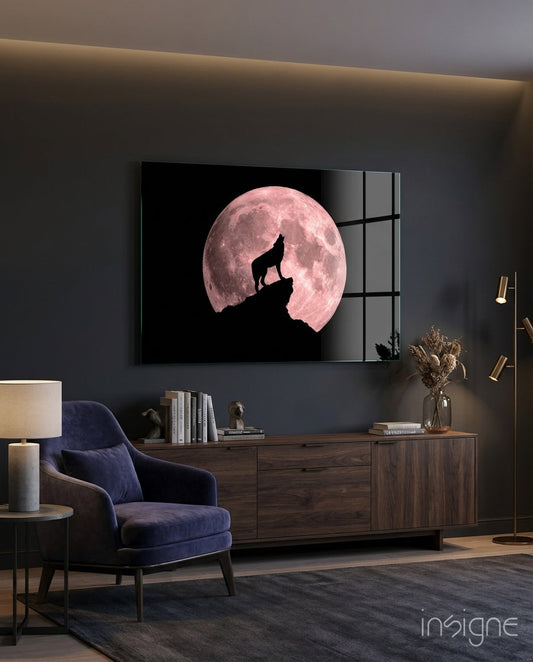 Wolf howling silhouette against pink full moon on black glass panel mounted above wooden media console in modern living room.
