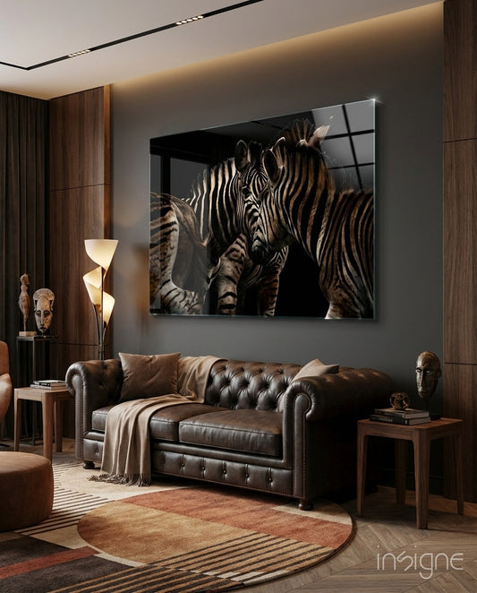 Framed glass wall art of two zebras nuzzling displayed above a brown leather sofa in a modern living room.
