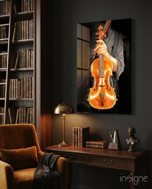 Violin glass wall art displaying a glowing amber violin with bow against black background, hung above wooden desk in library room.