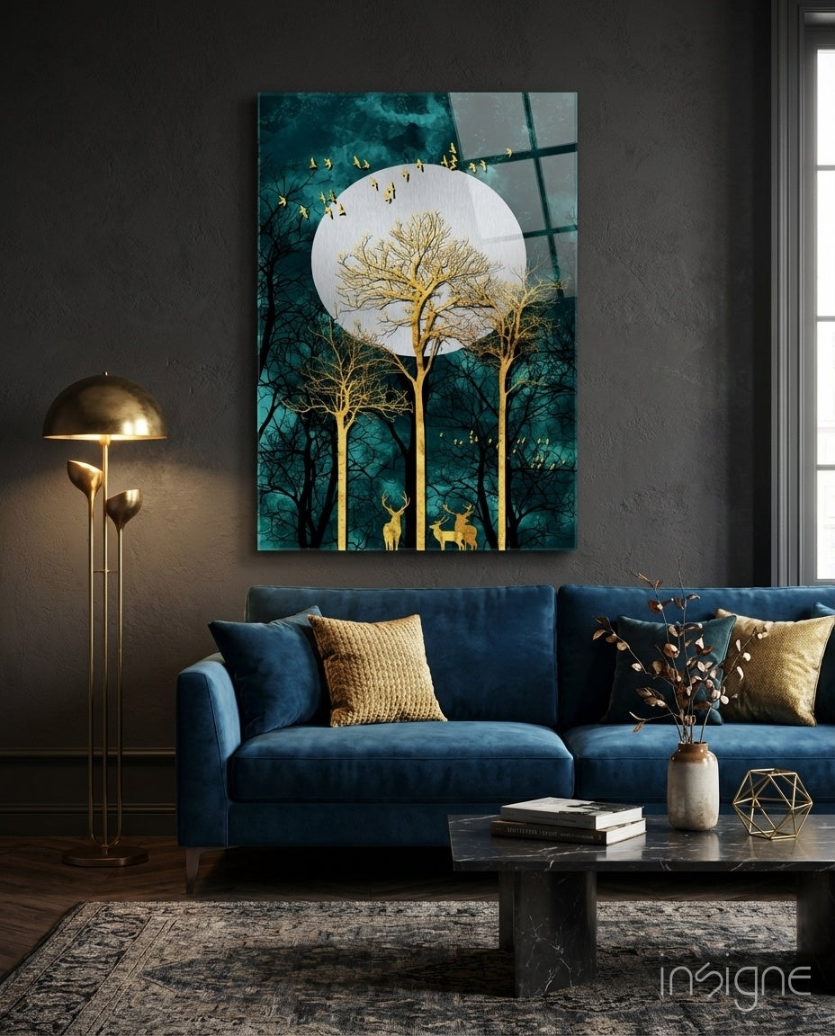 Night Glass Wall Art depicting golden trees, deer, and flying birds beneath a full moon against teal forest background, displayed above blue sofa in modern living room.