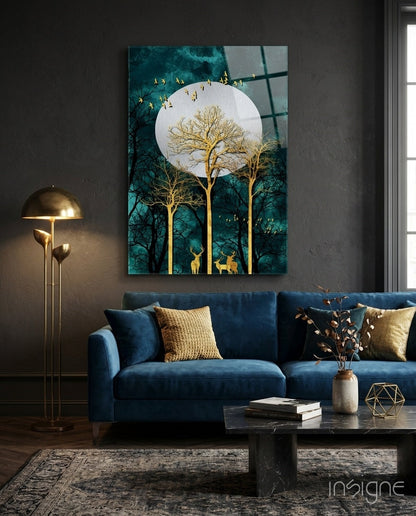 Night Glass Wall Art depicting golden trees, deer, and flying birds beneath a full moon against teal forest background, displayed above blue sofa in modern living room.