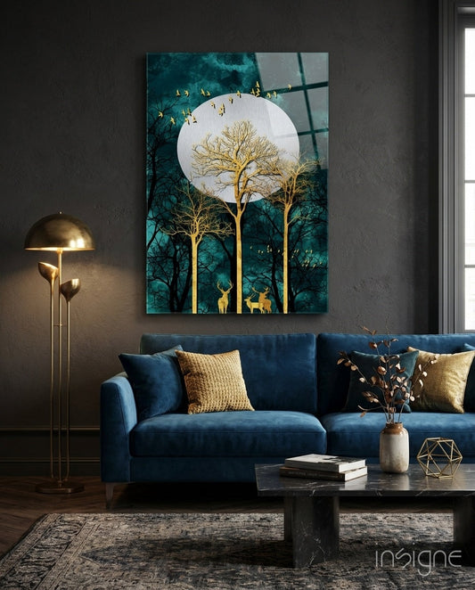 Night Glass Wall Art depicting golden trees, deer, and flying birds beneath a full moon against teal forest background, displayed above blue sofa in modern living room.