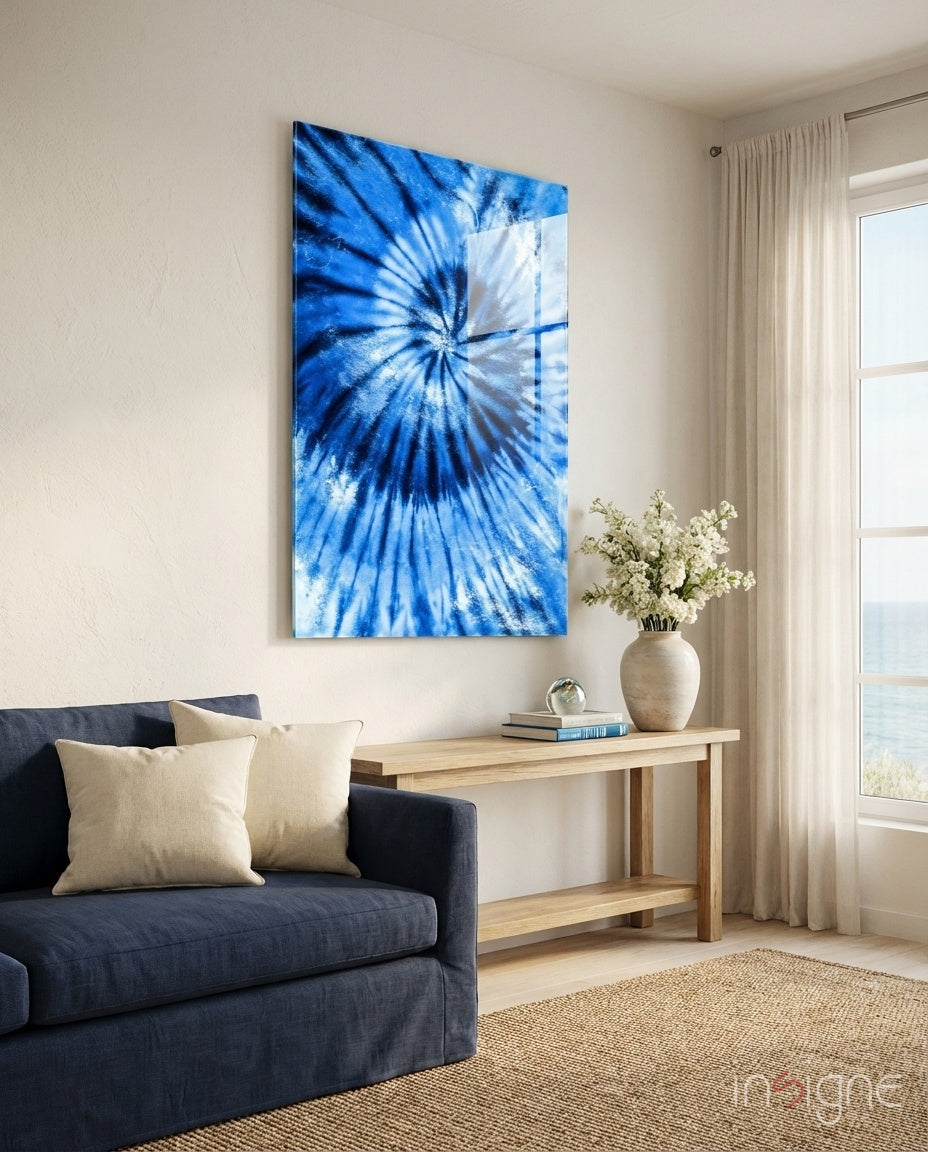 Blue radial tie-dye glass art hanging above a dark navy sofa in a bright, minimalist living room interior.