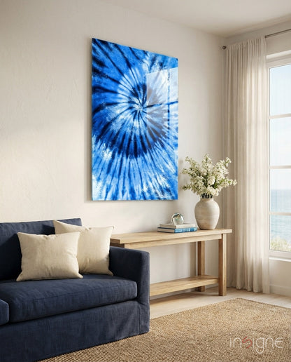Blue radial tie-dye glass art hanging above a dark navy sofa in a bright, minimalist living room interior.