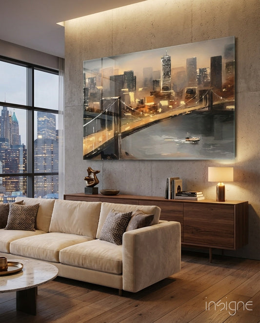 Modern living room with cream sofa displaying illuminated glass wall art of golden-lit suspension bridge over water at dusk above wooden console.