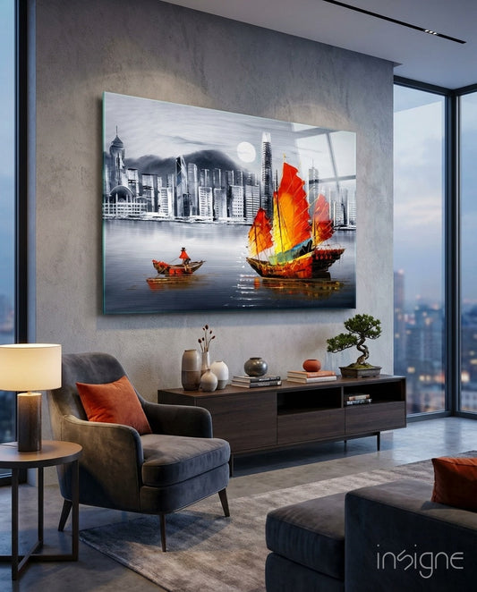 Modern living room with gray armchair and wooden console displaying glass wall art of red and yellow junk boat against monochrome Hong Kong skyline.